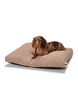 Ein kleiner braunhaariger Dackel liegt bequem auf dem rosafarbenen WAVY-Modellbett von John Dog. Das Bett hat eine gestreifte Textur und weiches Material, das deinem Hund Komfort bietet.