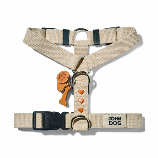 Beigefarbenes Hundegeschirr aus Baumwollgurtband aus der MANIFEST Kollektion von John Dog. Das Geschirr hat einen Schlüsselring aus Leder mit einem Knochen, einer Hundepfote und einem Herz sowie Nieten in Form von braunen Herzen.