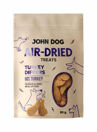 Vorderseite der Packung John Dog Air-Dried Turkey Dippers Leckerlis. Sichtbarer Produktname, Abbildung eines Hundes und Blick auf die Leckerlis im Inneren.