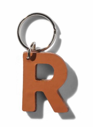 Brauner Lederschlüsselanhänger für Leine, Geschirr oder Halsband in Form des Buchstabens "R" aus der MANIFEST Kollektion von John Dog. Der Schlüsselanhänger kann als Initiale für den Namen deines Hundes verwendet werden.